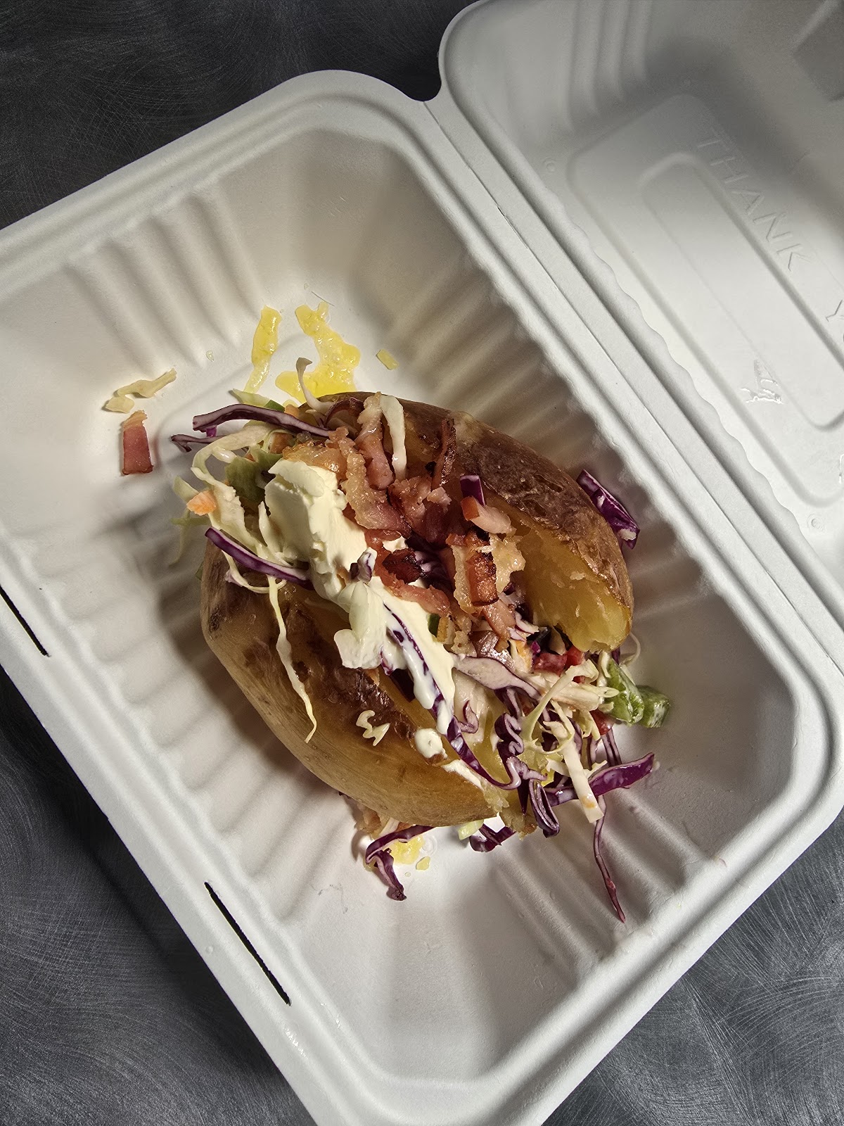 A baked potato with all the toppings, boxed to take away